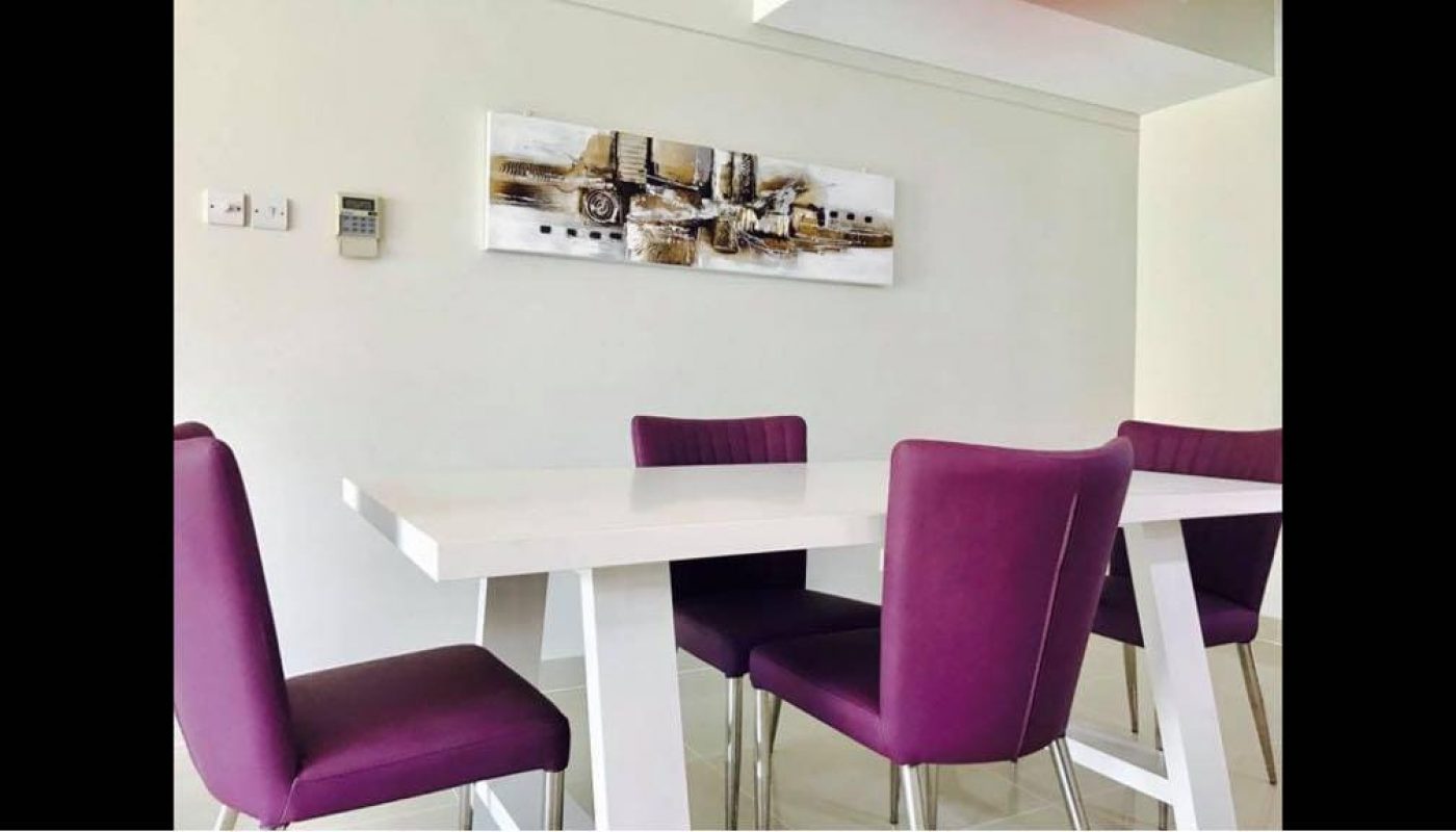 A fully furnished apartment with a purple chair and a white table in the dining room.