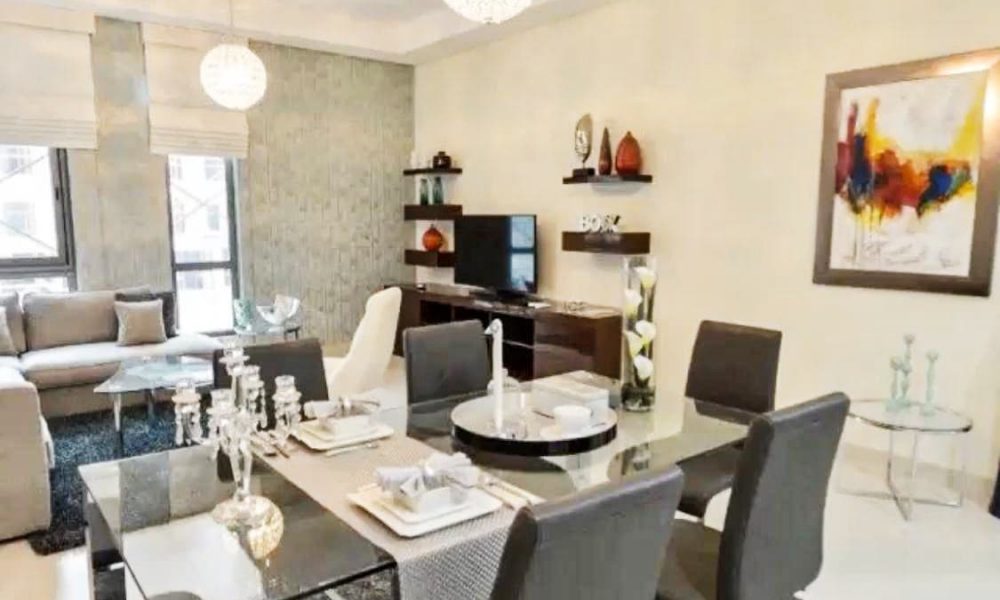 A living room with a dining table and chairs in an amazing apartment for sale in Isa Town.