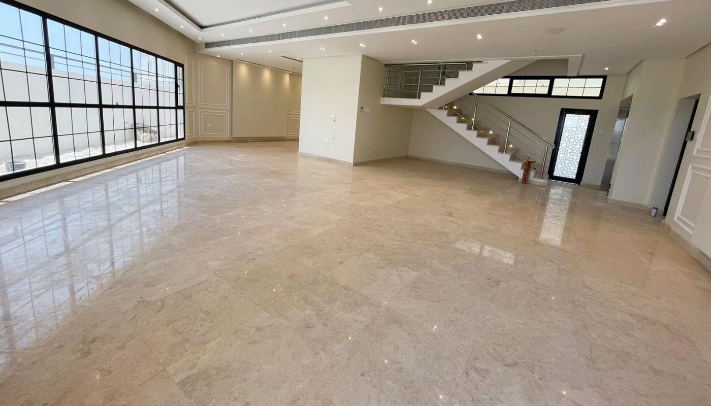 A spacious, empty room with large windows, beige marble flooring, recessed ceiling lights, and a staircase leading to an upper level creates a perfect canvas for any auto draft design projects.