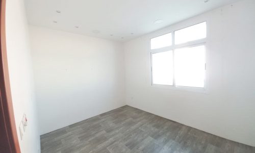 An empty apartment with white walls and wooden floors available for sale.