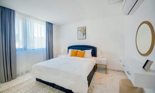 Luxury bedroom with white bed and orange accents in a 2BR FF Flat for Rent in Seef.