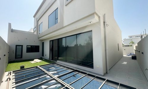 A modern villa in Hamala with a large glass door and a grassy area.