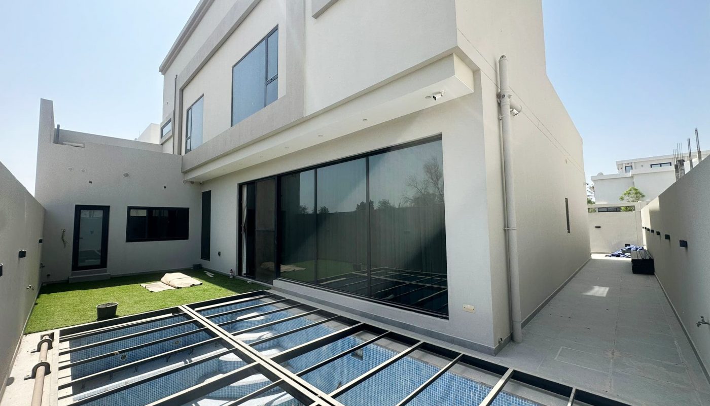 A modern villa in Hamala with a large glass door and a grassy area.