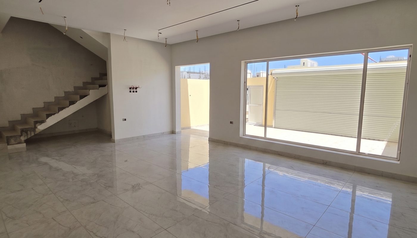Empty modern room with marble floors, large windows, an unfinished ceiling with exposed wires, and a staircase leading upstairs.