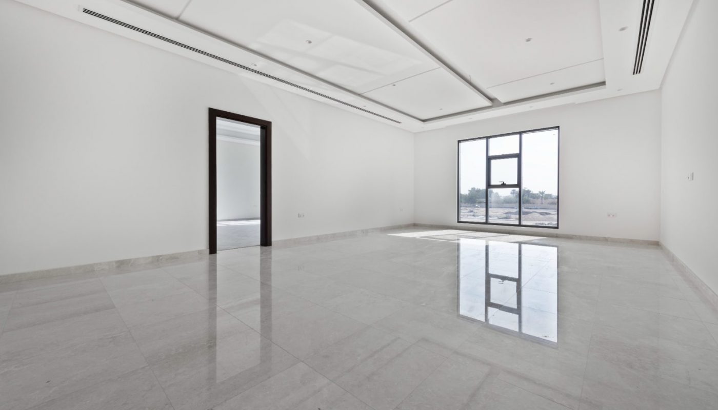 Spacious empty room with white walls, large window, and marble floor, with a single open doorway on the left side.