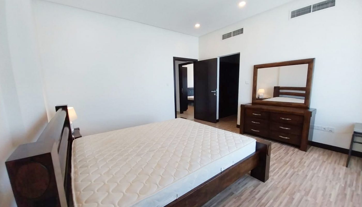A luxury bedroom in a 2-bedroom apartment furnished with a bed, dresser, and mirror.