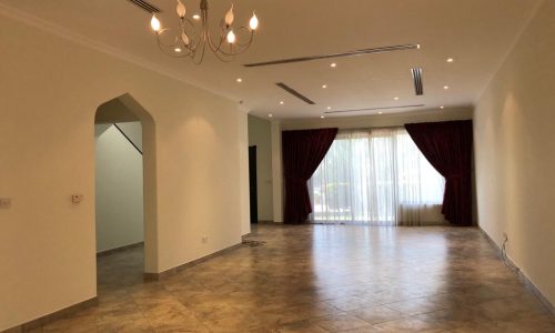 Spacious living room with tiled floors, a chandelier, large burgundy curtains, recessed lighting, and an arched entryway.