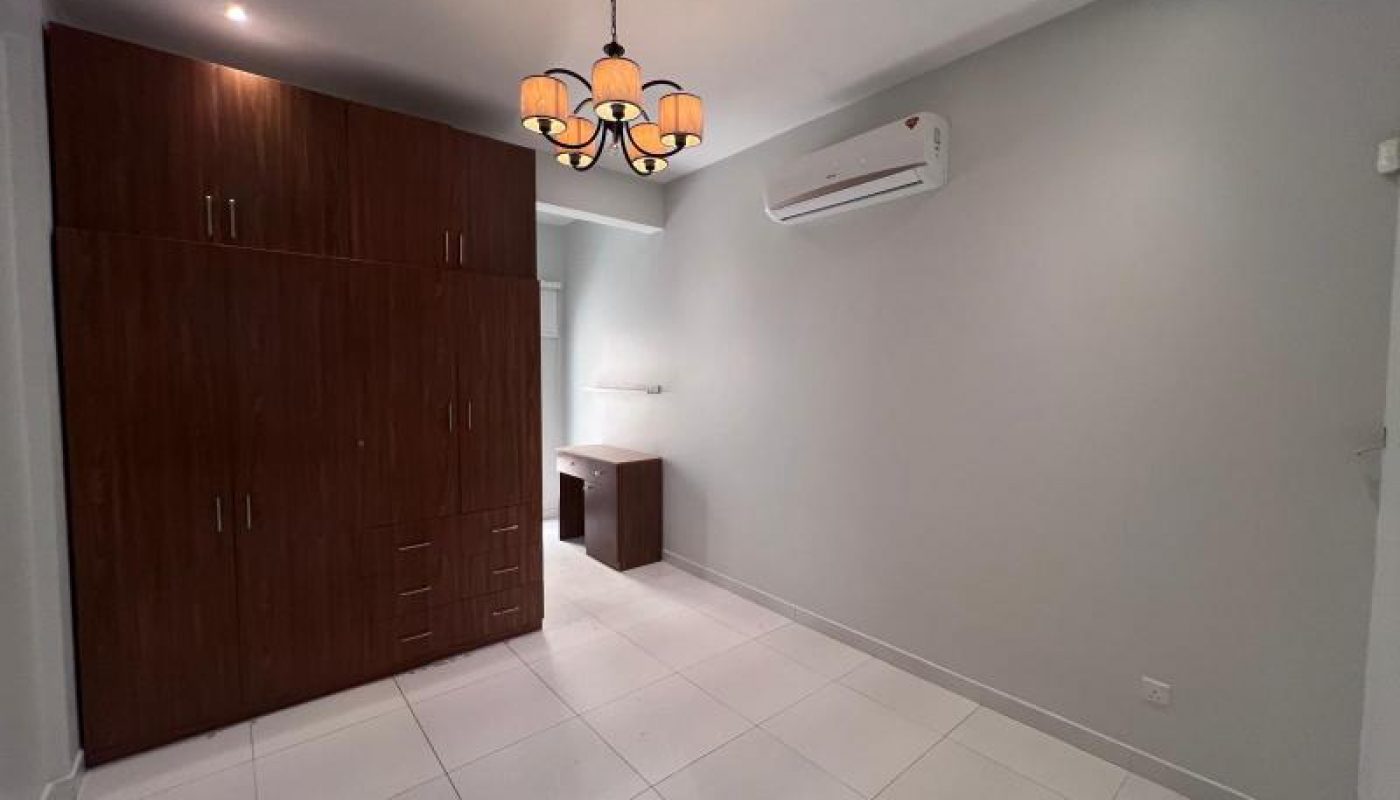 A minimal bedroom with white tiled floor, a wooden wardrobe, a desk, wall-mounted air conditioner, and a ceiling light fixture.