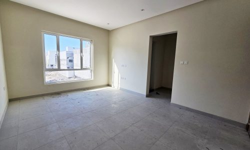 Empty room with tiled floor, a large window, beige walls, and an auto draft leading to another room.