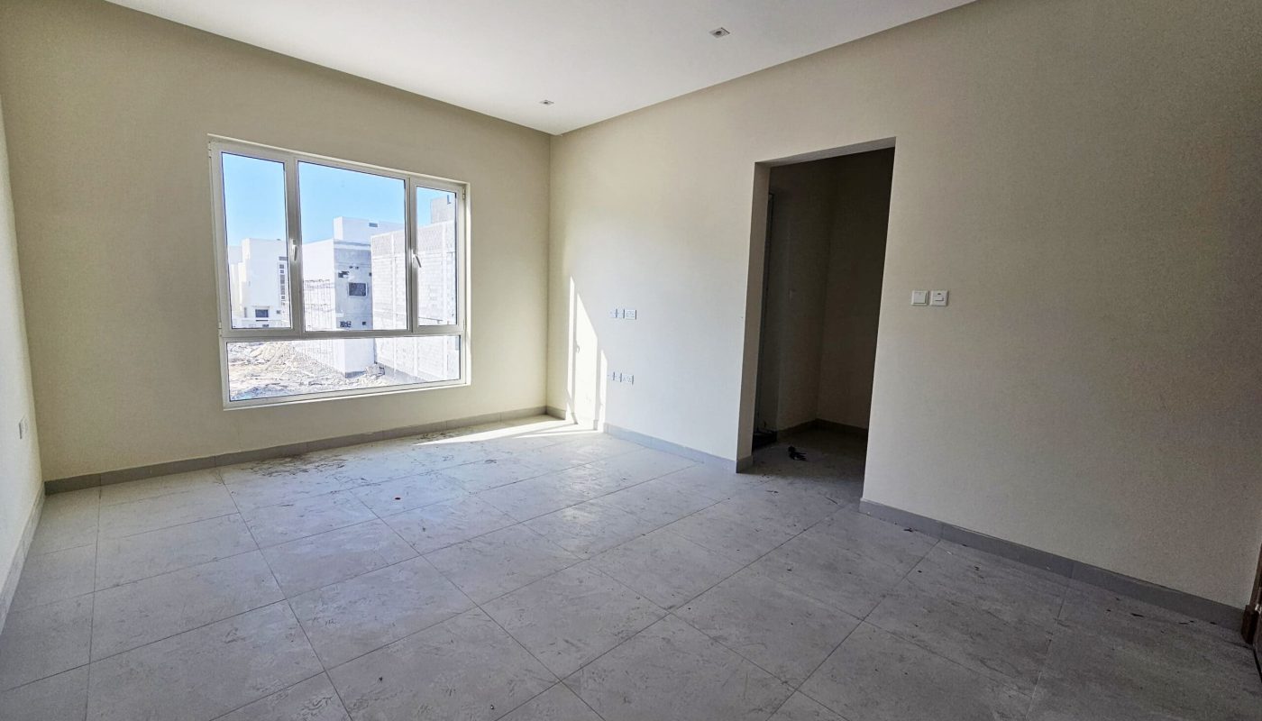 Empty room with tiled floor, a large window, beige walls, and an auto draft leading to another room.