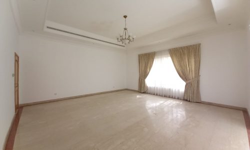 A large empty room with white walls and a chandelier.