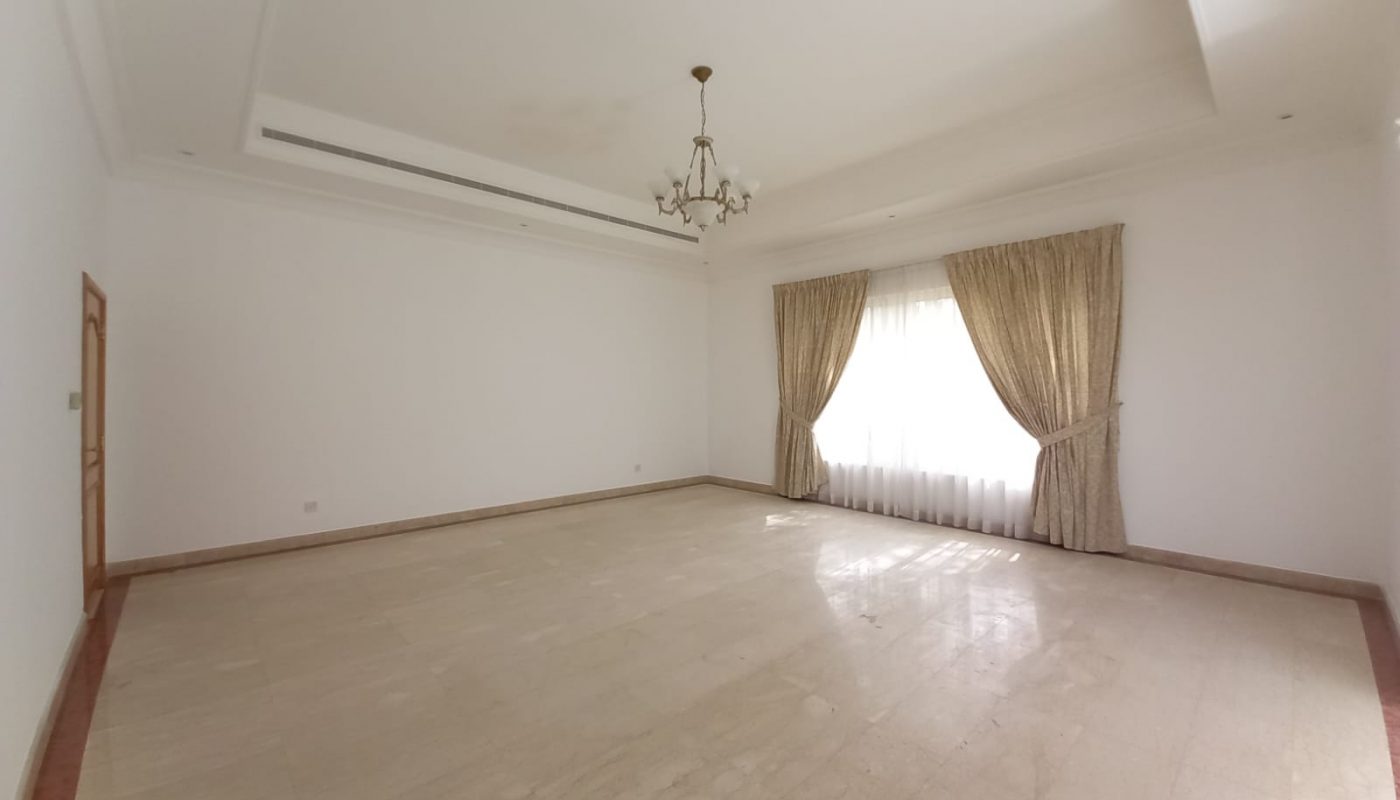 A large empty room with white walls and a chandelier.