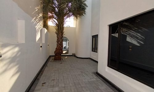 A spacious hallway in a luxury villa with a palm tree in the middle.