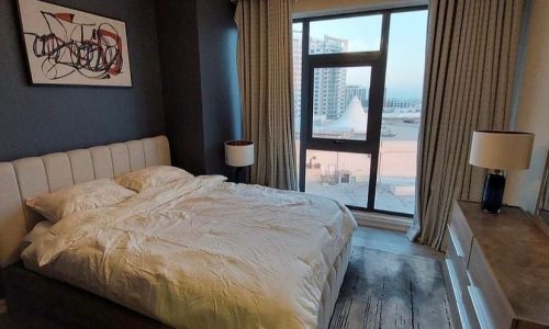 Luxury bedroom with a view of the city in a fully furnished apartment for sale in Amwaj Island.