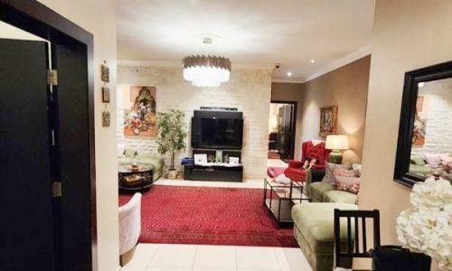 A living room in a luxury apartment in Tubli with a chandelier.