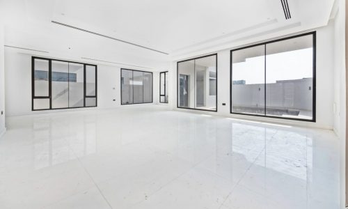 A large empty room with white tile floors and large windows.