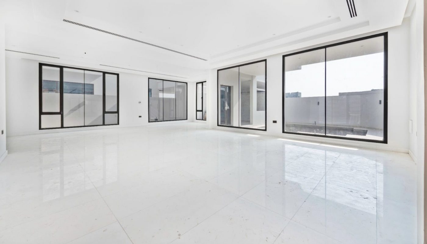 A large empty room with white tile floors and large windows.