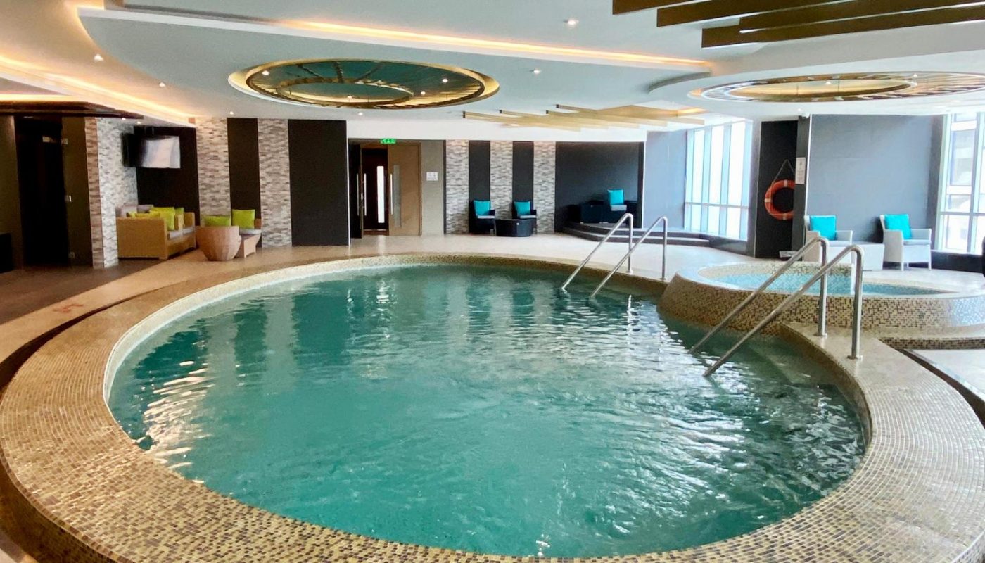 Indoor circular pool with tiled edge, entry steps, and seating area in the background; depth marking "4' - 7"" in red on the floor in front.