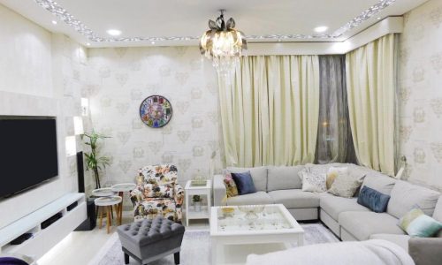 Luxury living room with white furniture and a tv.