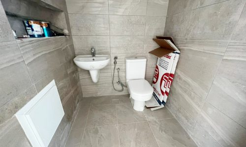 A small bathroom with a toilet and sink in an Amazing New 4BR Villa in Durrat Al Muharraq.