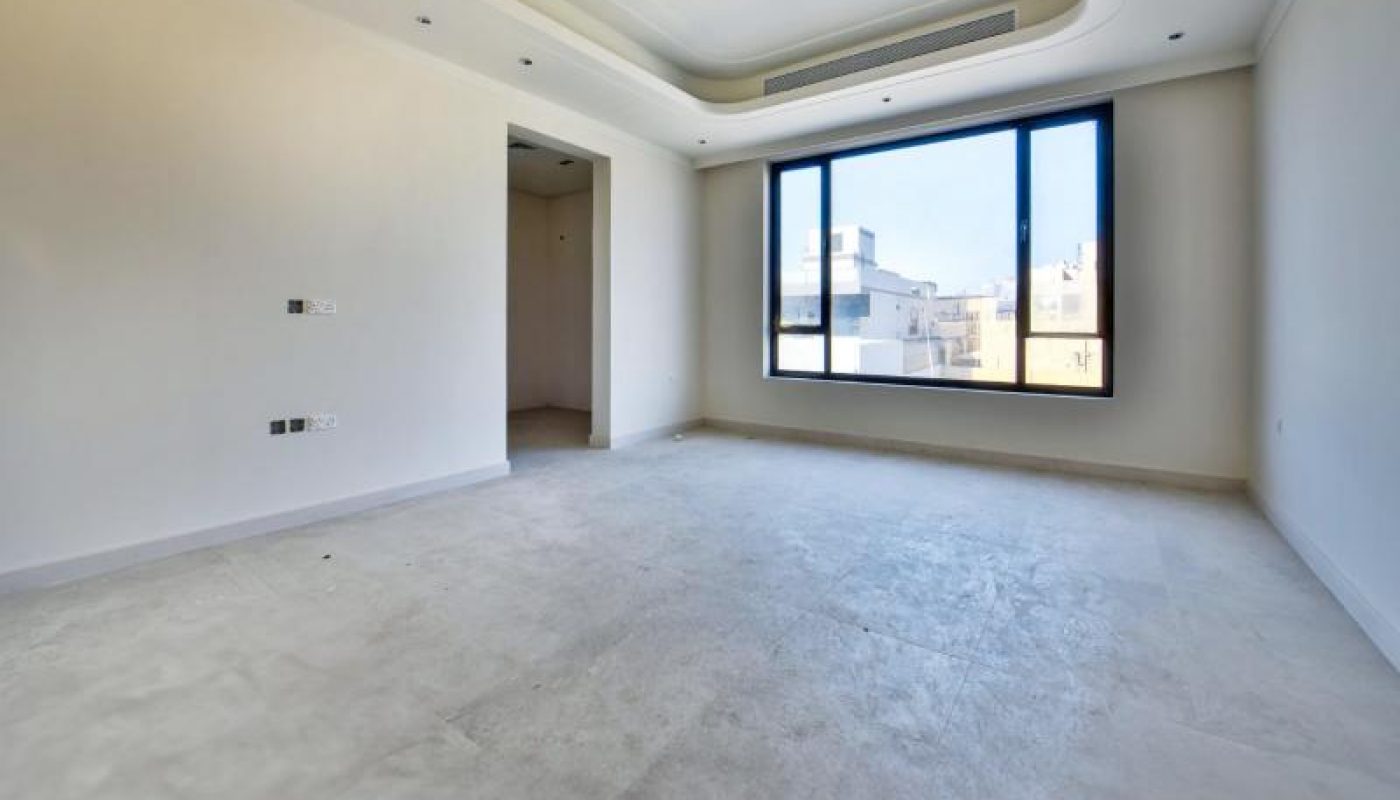 Unfurnished, empty room with large windows, white walls, and a recessed ceiling, receiving natural light from outside.