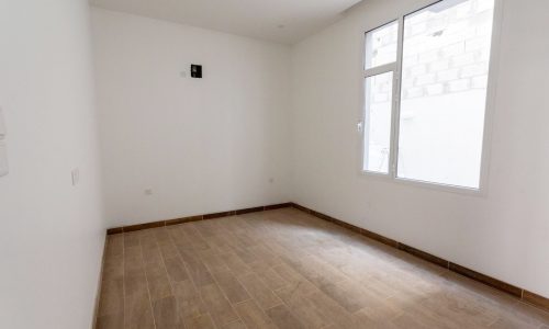 A spacious room with wooden floors and white walls.