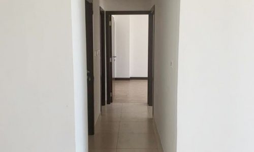 An empty hallway with white tiles and a door available in the Heart of Amwaj.