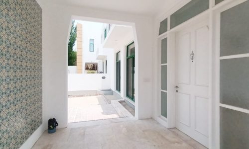 A commercial villa in Adliya available for rent, featuring a hallway with a white door and tiled walls.