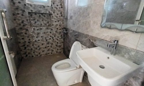 Luxury bathroom with toilet, sink, and mirror in Deluxe 4BR Apartments.