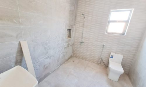 A mesmerizing bathroom with a toilet, sink, and window in a 4BR Villa for Sale in Malkiyah.