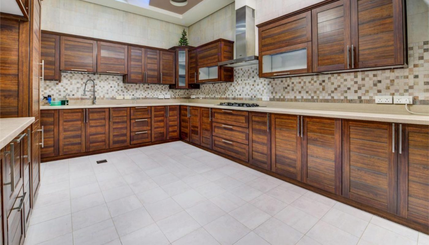 Spacious modern kitchen with dark wood cabinets, tile backsplash, light countertops, and patterned ceiling featuring recessed lighting and circular accents.