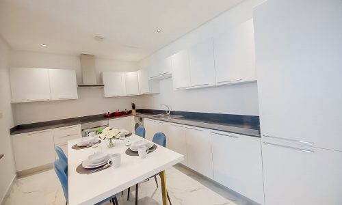 A luxury kitchen with white cabinets and marble counter tops.