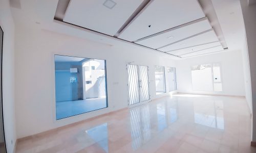 A luxurious villa for sale in Bu Quwah with a glass floor and white walls.