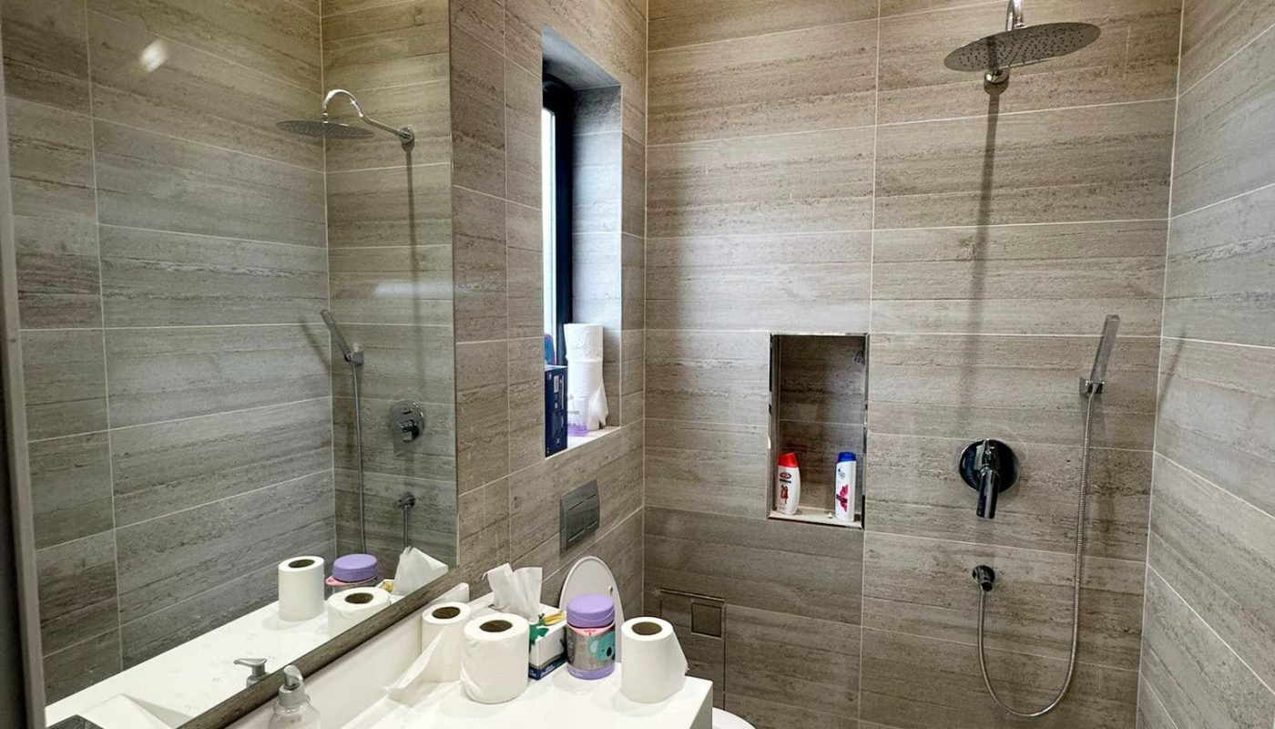 A modern villa with a bathroom equipped with a toilet, sink, and shower.