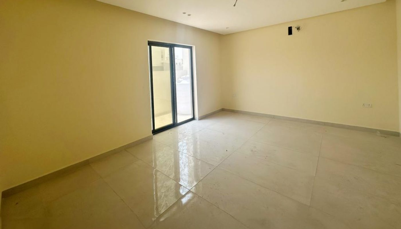 Empty, unfurnished room with beige walls and a tiled floor, featuring a large sliding glass door that opens to the outside. Ceiling light fixture is not installed.
