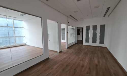 A spacious office blanketed with natural brightness, featuring wood floors and mirrors, available for rent in the Seef area.