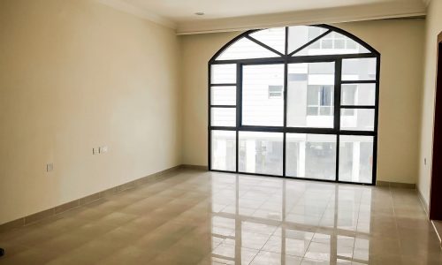 A spacious room with a large window, tiled floor, and modern design.