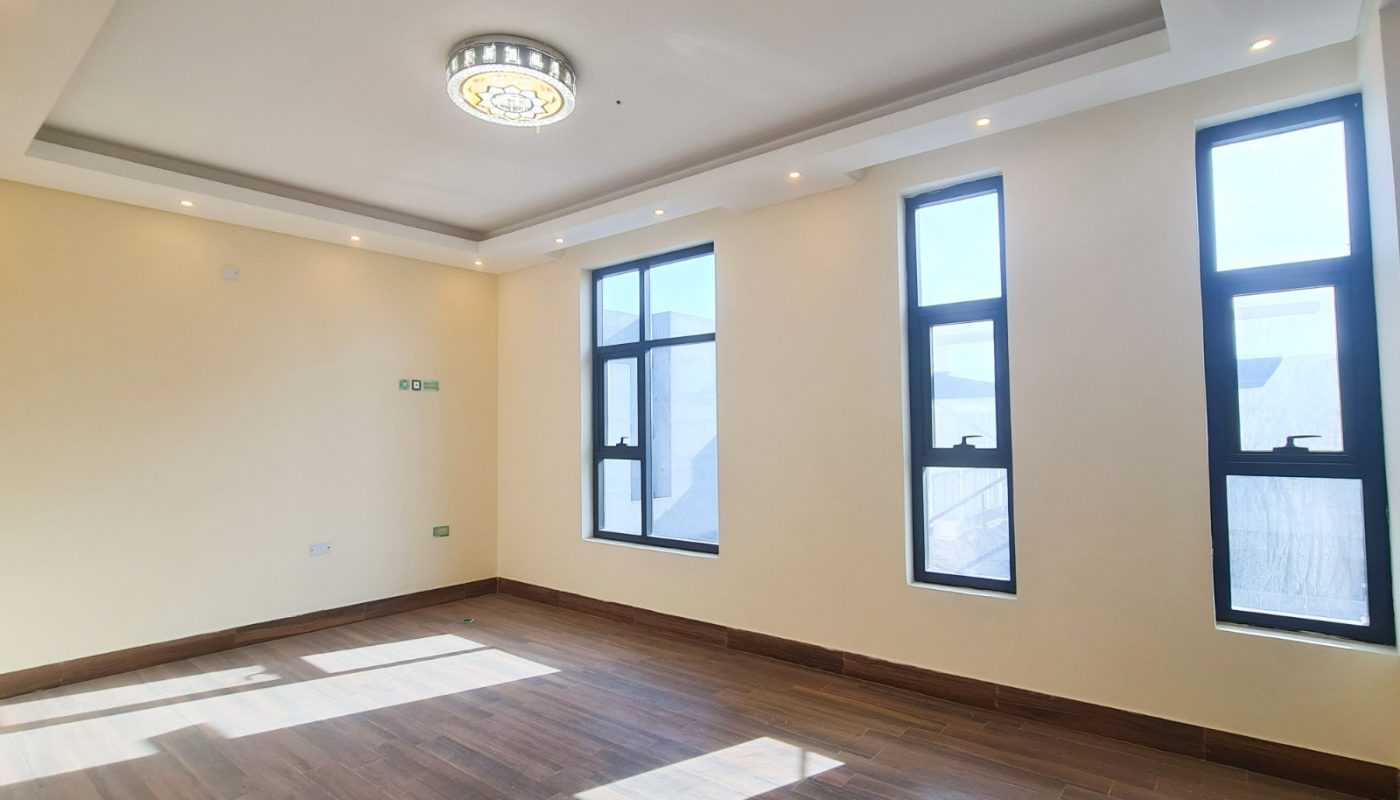 A luxury villa for sale in Sitra with large windows and wooden floors.