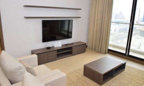 A fully furnished living room with a flat screen tv.