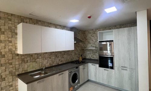 A flat in Amwaj available for rent, featuring a convenient kitchen with an integrated washer and dryer.