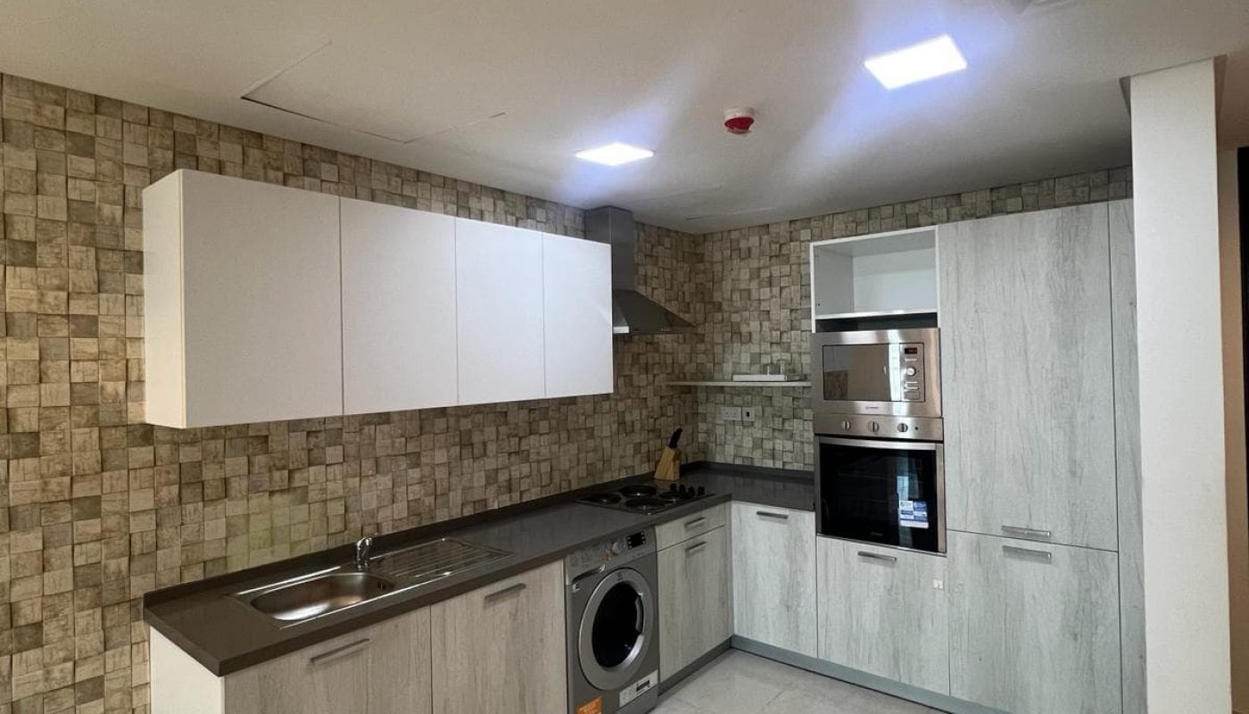 A flat in Amwaj available for rent, featuring a convenient kitchen with an integrated washer and dryer.