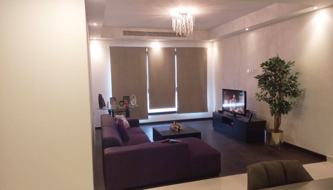 A luxury living room with a purple couch and TV.