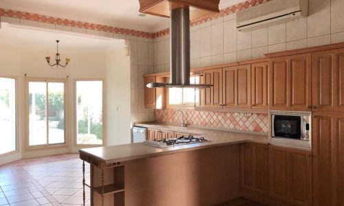 A luxury kitchen with wooden cabinets and a stove in a 3BR SF Villa for Rent in Saar.