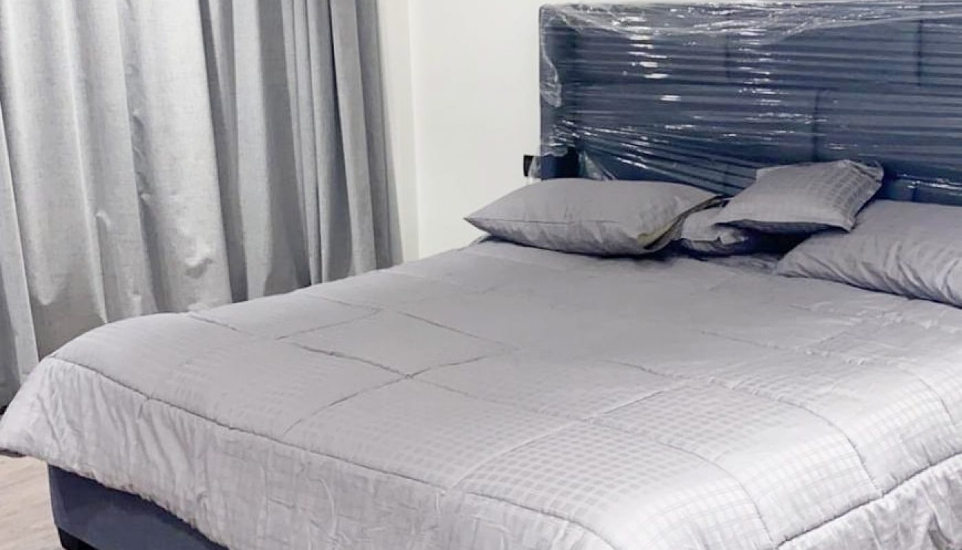 A fully furnished bedroom with a grey comforter available in an apartment for rent in Dilmunia.