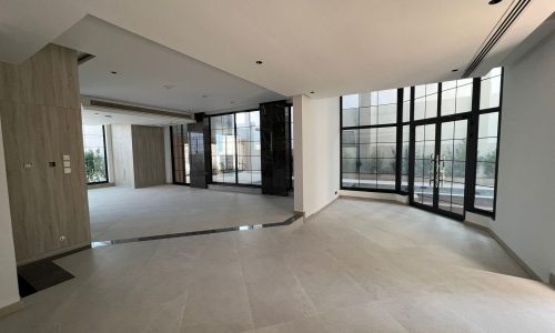 A huge living room in a luxurious villa with large windows.