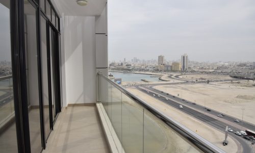 A fully furnished 1BR flat with a view of the city from a balcony overlooking the water.