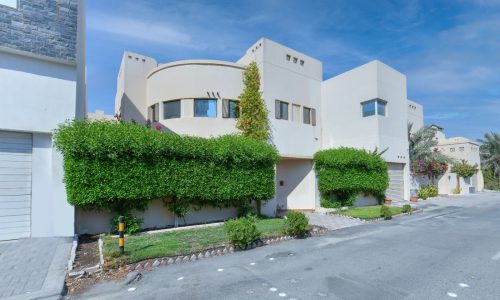 Stunning house in the middle of a street surrounded by trees and shrubs.