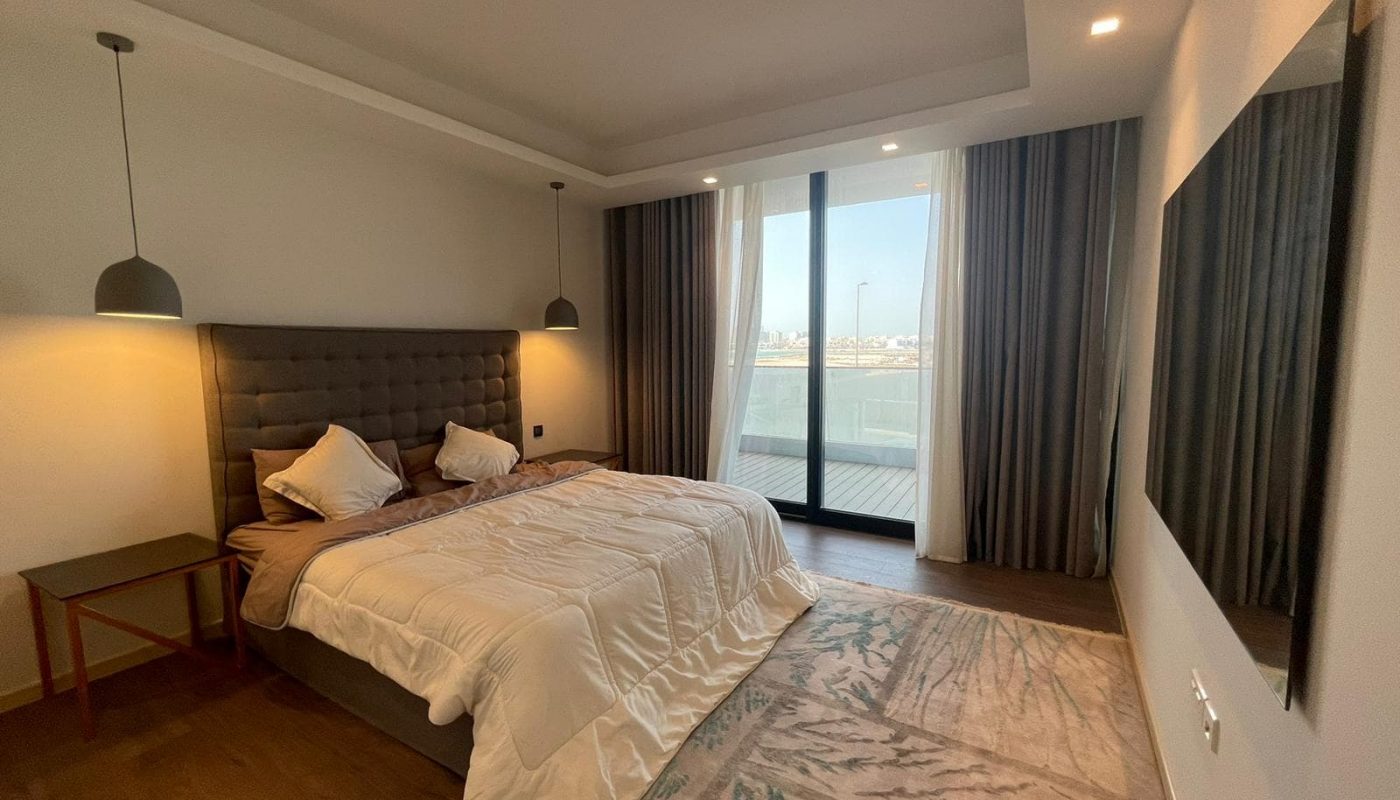 An elegant bedroom with a large bed and a view of the water for sale.