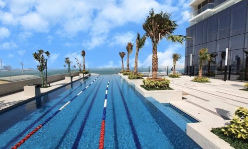 A swimming pool in front of a building with palm trees is available for sale in Juffair.