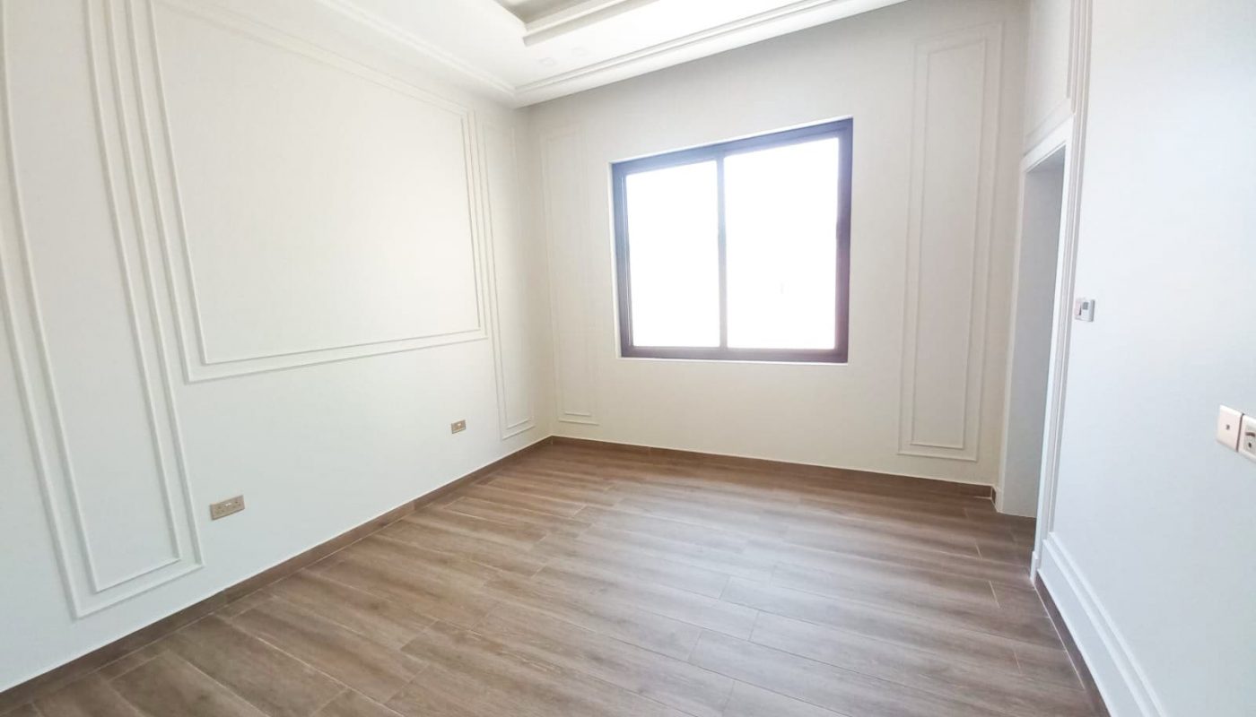 A spacious room with white walls and wood floors in a luxury villa.